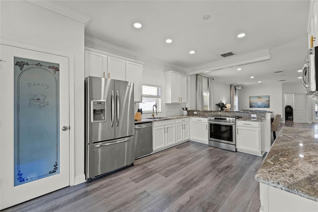 kitchen with visible vents, appliances with stainless steel finishes, a peninsula, and white cabinetry