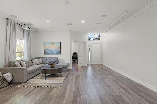 living area featuring visible vents, baseboards, wood finished floors, and ornamental molding