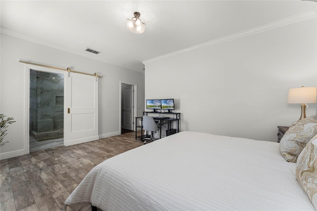 bedroom featuring visible vents, wood finished floors, a barn door, crown molding, and baseboards