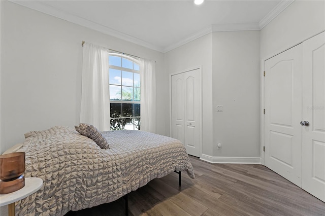 bedroom with a closet, baseboards, wood finished floors, and ornamental molding