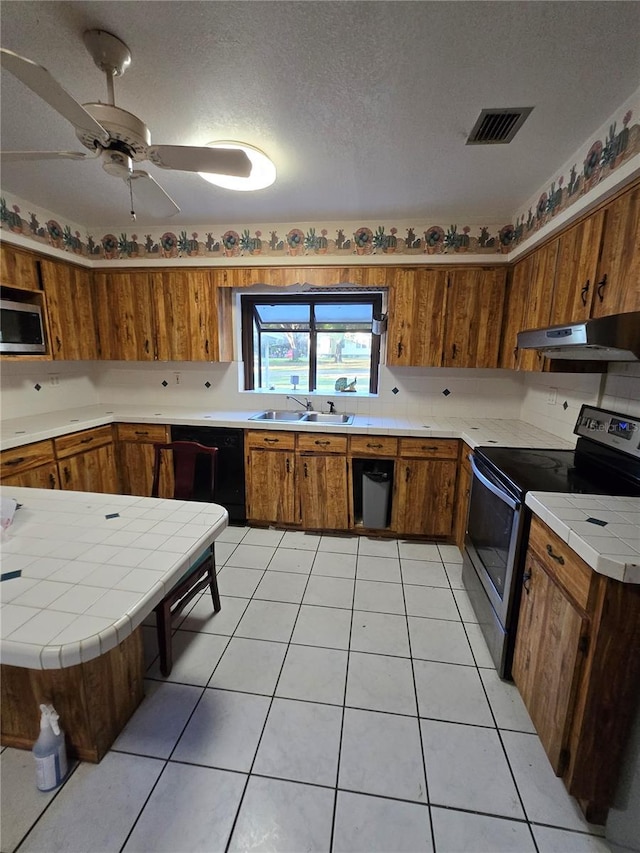 kitchen with visible vents, under cabinet range hood, a sink, stainless steel appliances, and brown cabinetry