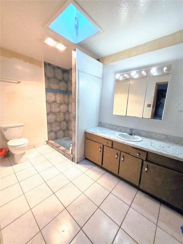 full bathroom featuring tile patterned floors, toilet, tiled shower, and vanity