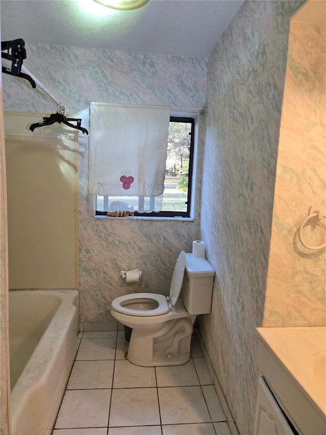 full bathroom featuring washtub / shower combination, toilet, vanity, and tile patterned flooring