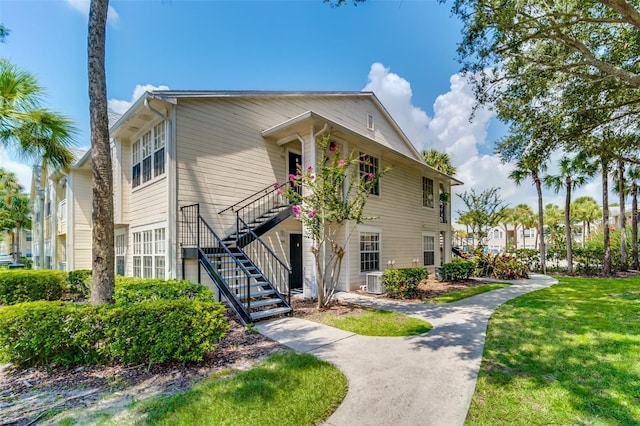 view of front of property featuring stairway, central air condition unit, and a front lawn