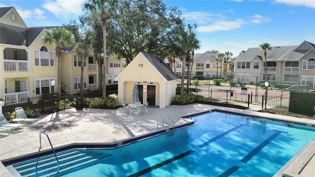 community pool featuring a patio area, fence, and a residential view