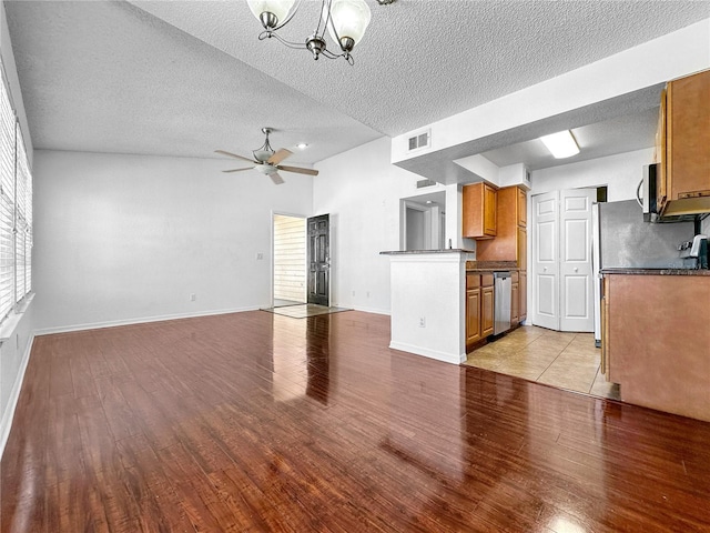 unfurnished living room with visible vents, ceiling fan with notable chandelier, a textured ceiling, and light wood finished floors