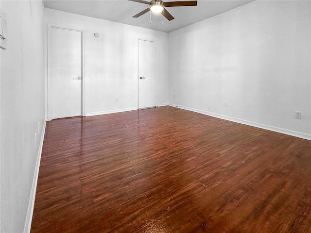 empty room with dark wood finished floors, baseboards, and a ceiling fan