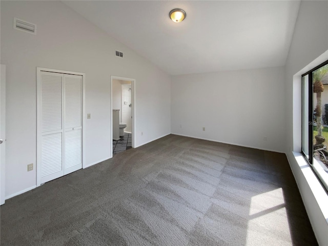 unfurnished bedroom featuring visible vents, high vaulted ceiling, ensuite bath, and carpet flooring