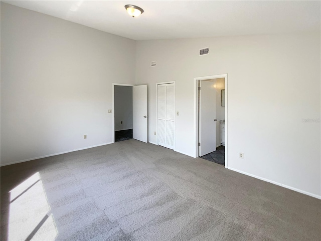 unfurnished bedroom featuring visible vents, high vaulted ceiling, ensuite bathroom, carpet floors, and baseboards