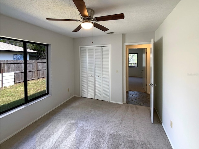 unfurnished bedroom featuring visible vents, baseboards, carpet floors, a closet, and a textured ceiling