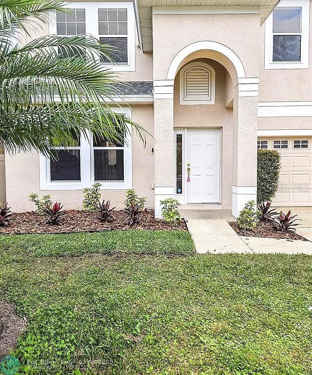 property entrance with stucco siding and a lawn