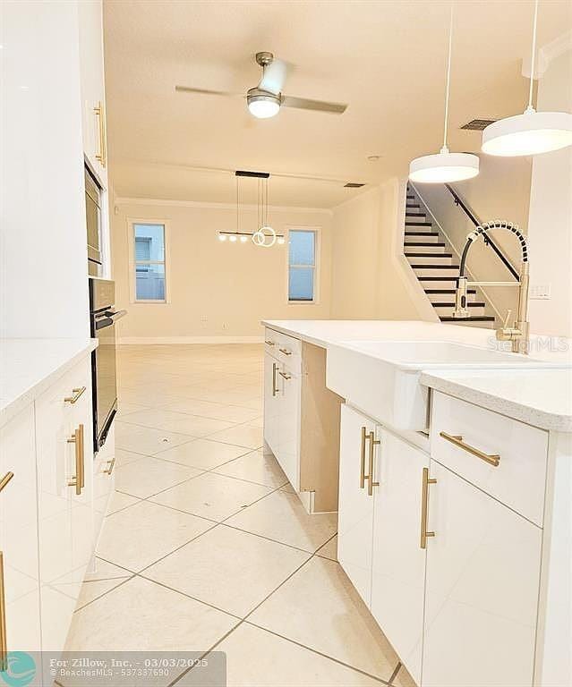 kitchen featuring oven, modern cabinets, decorative light fixtures, white cabinets, and light tile patterned flooring