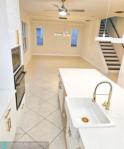 interior space with stainless steel microwave, oven, ceiling fan, light countertops, and a sink