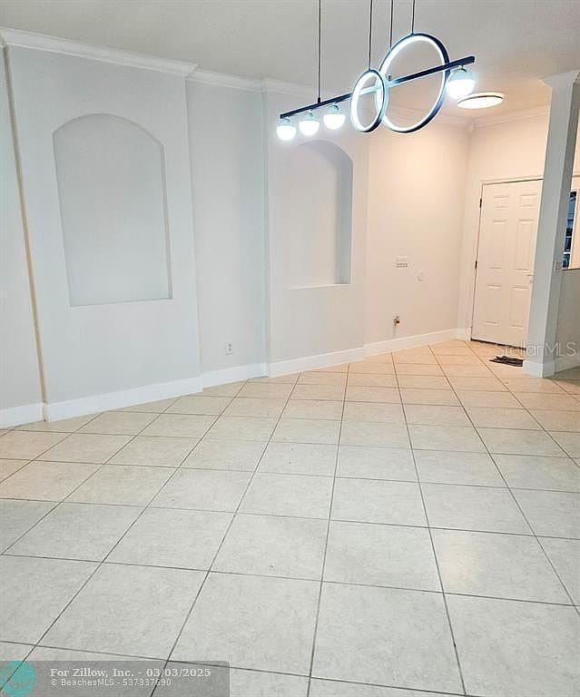 tiled spare room with crown molding and baseboards