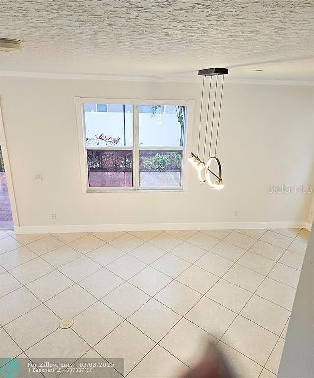 spare room featuring a textured ceiling, baseboards, and ornamental molding