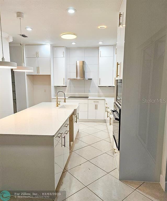 kitchen with black appliances, white cabinets, wall chimney exhaust hood, and light tile patterned floors