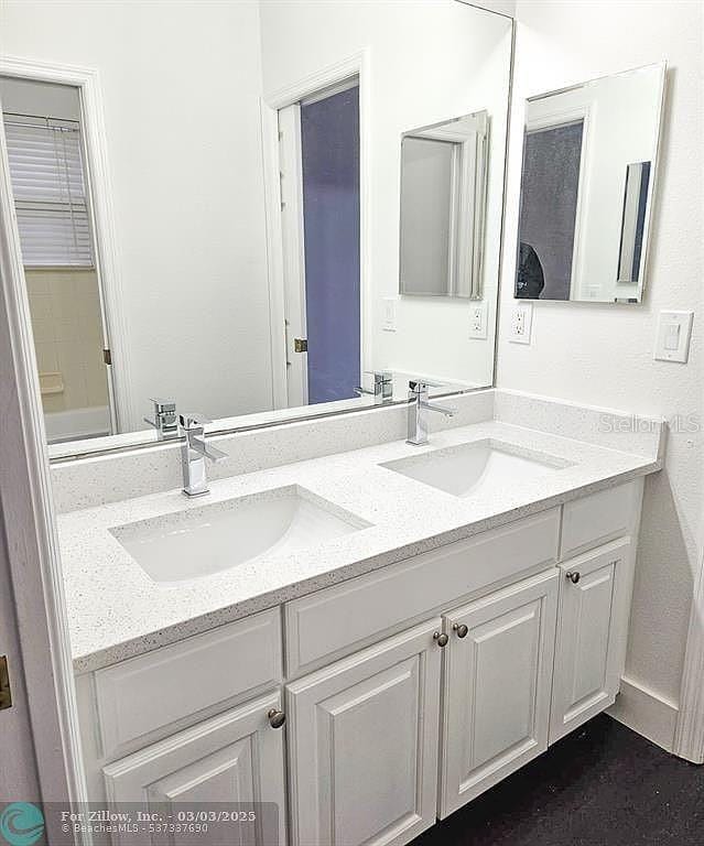 bathroom with double vanity, baseboards, and a sink