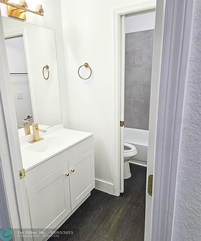 bathroom featuring vanity, toilet, wood finished floors, and baseboards