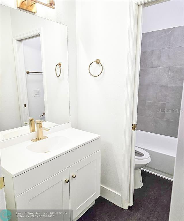 full bathroom featuring tub / shower combination, baseboards, toilet, and vanity