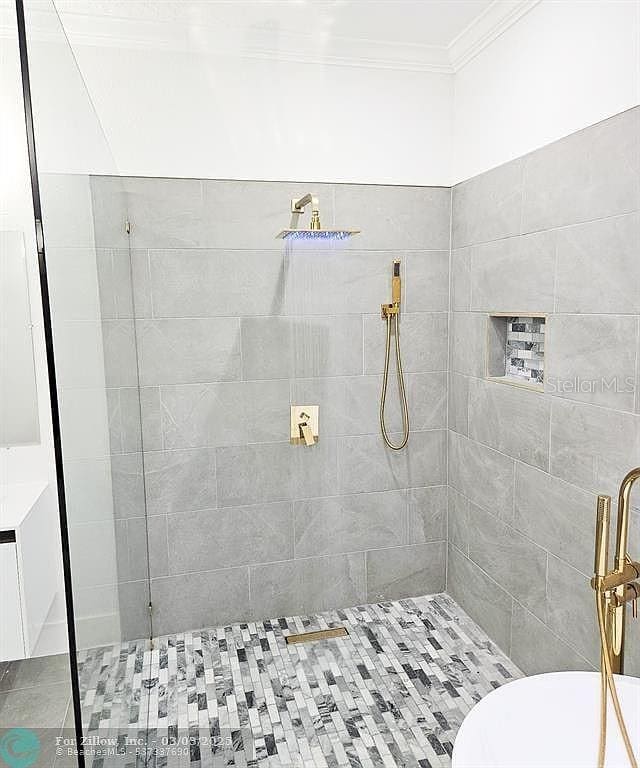 full bathroom featuring tiled shower and crown molding