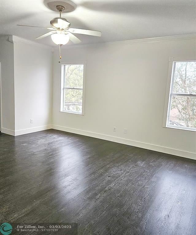 unfurnished room with dark wood-type flooring, a healthy amount of sunlight, ornamental molding, and a ceiling fan