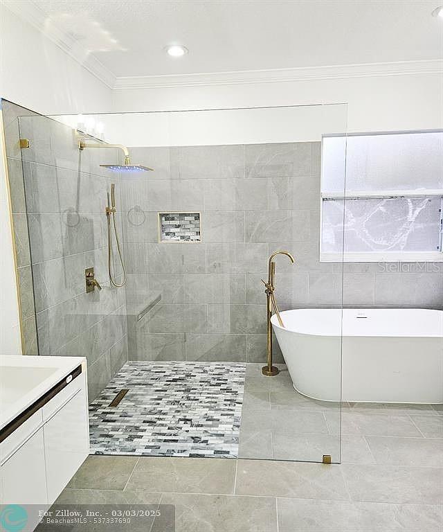 full bath featuring vanity, a freestanding bath, walk in shower, and crown molding