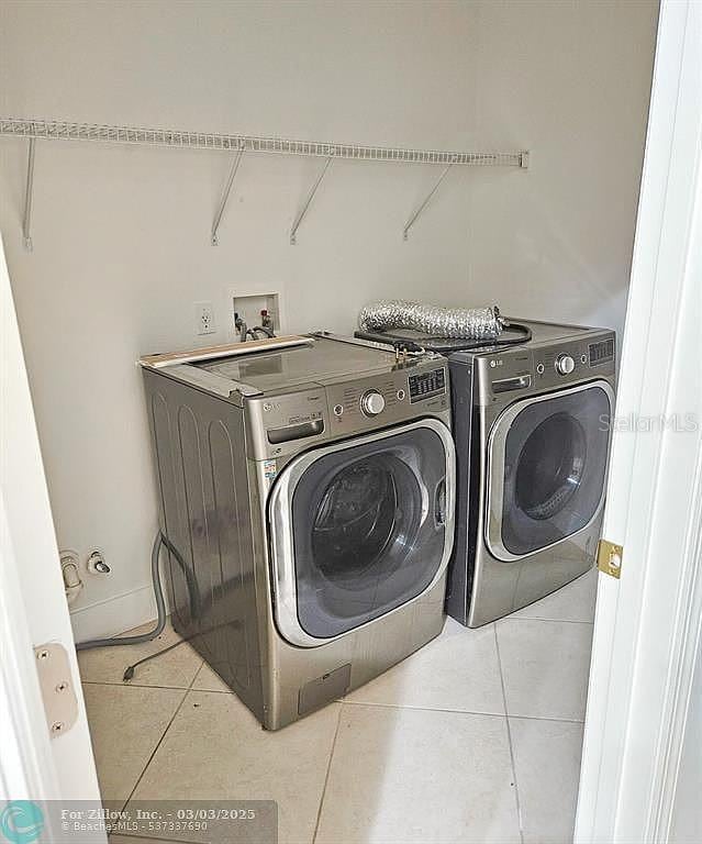 washroom featuring tile patterned floors, laundry area, and washing machine and clothes dryer