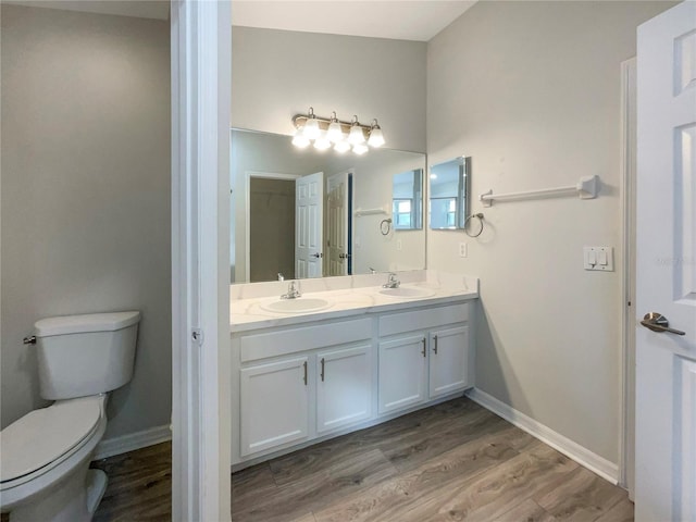 bathroom with a sink, baseboards, toilet, and wood finished floors