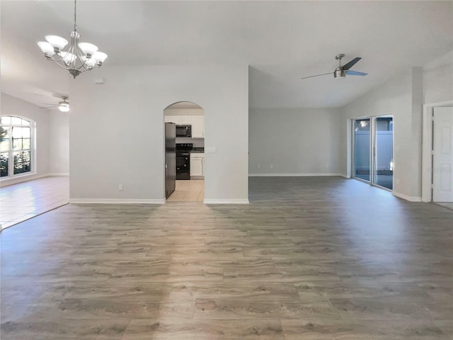 unfurnished living room featuring light wood-type flooring, lofted ceiling, ceiling fan with notable chandelier, arched walkways, and baseboards