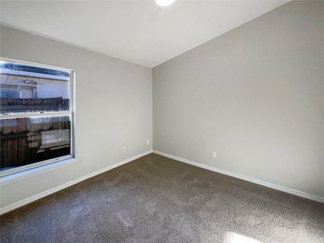 unfurnished room featuring dark colored carpet and baseboards