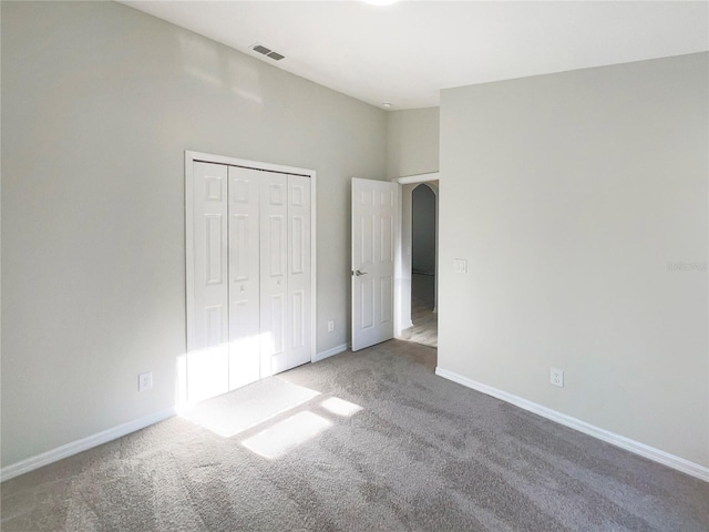 unfurnished bedroom with visible vents, baseboards, a closet, and carpet flooring