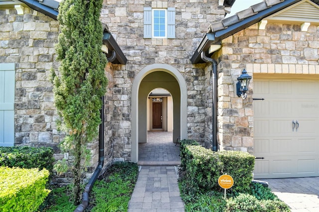 property entrance with stone siding and an attached garage