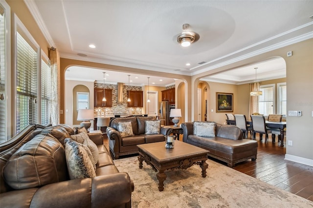 living room with arched walkways, wood-type flooring, and ornamental molding