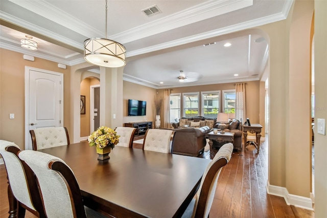 dining room with visible vents, dark wood-type flooring, baseboards, ornamental molding, and arched walkways