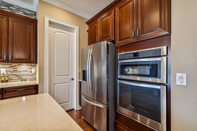 kitchen with dark wood-type flooring, tasteful backsplash, stainless steel appliances, crown molding, and light stone countertops