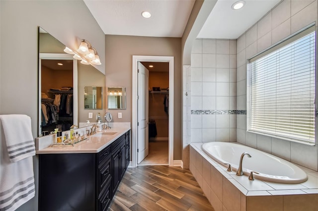 full bath with a bath, vanity, a wealth of natural light, and wood finished floors