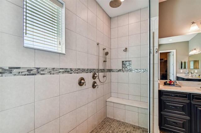 bathroom with a tile shower and vanity