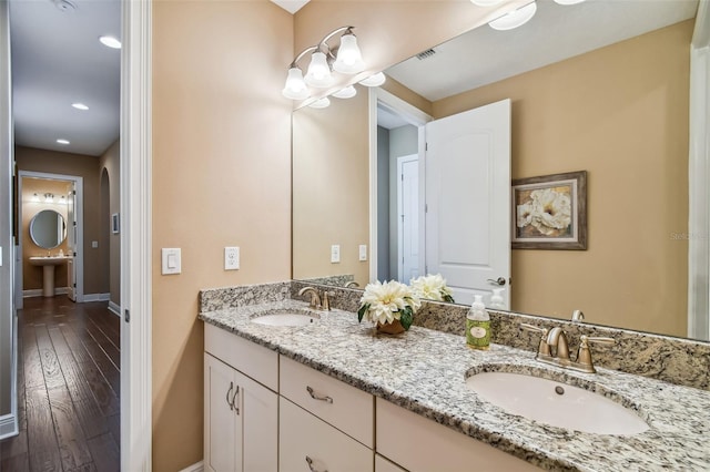 full bathroom with a sink, visible vents, baseboards, and wood finished floors