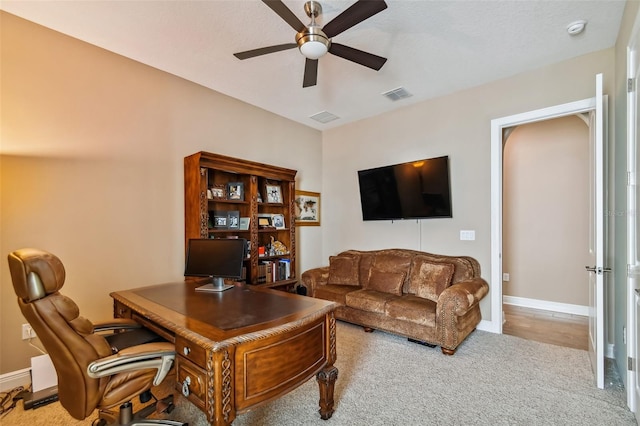 carpeted office featuring visible vents, baseboards, and a ceiling fan