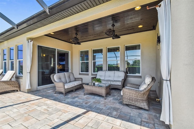 view of patio / terrace featuring glass enclosure, an outdoor hangout area, and a ceiling fan