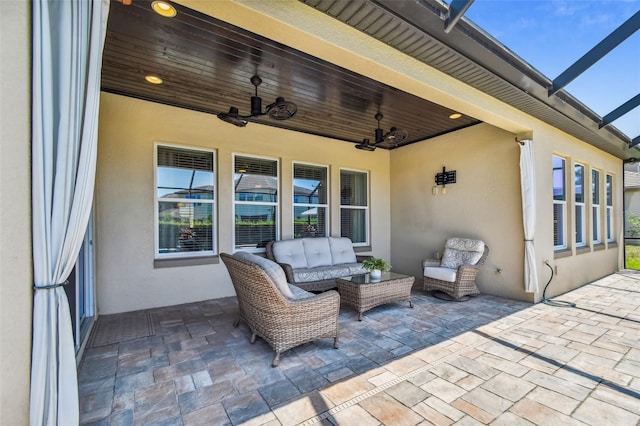 view of patio with glass enclosure, an outdoor living space, and ceiling fan