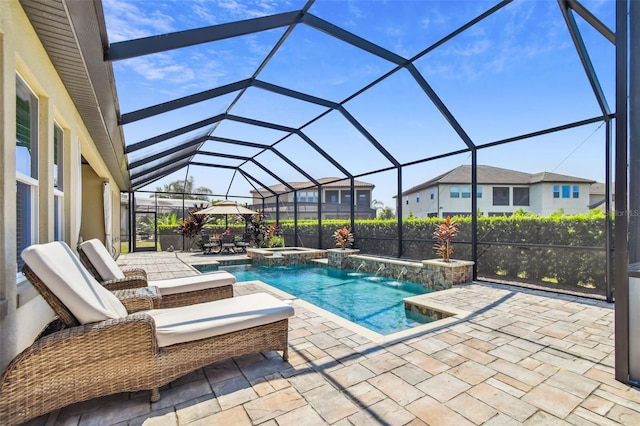 view of swimming pool with a patio area, glass enclosure, and a pool with connected hot tub