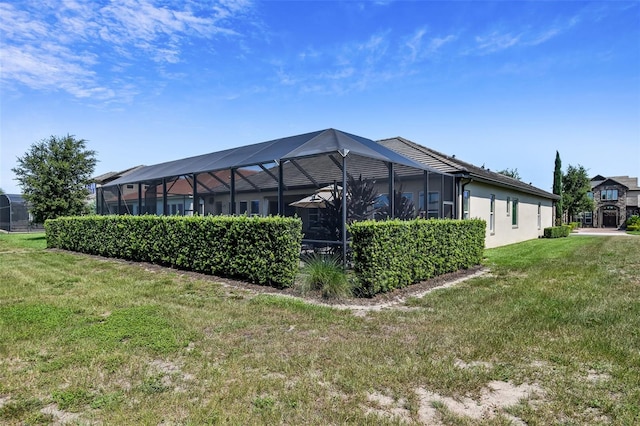 back of property featuring a yard, glass enclosure, and stucco siding