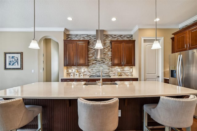 16736 Broadwater Ave, Winter Garden, FL 34787 - kitchen featuring wall chimney range hood, decorative backsplash, a kitchen bar, ornamental molding, and stainless steel refrigerator with ice dispenser
