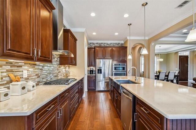 16736 Broadwater Ave, Winter Garden, FL 34787 - kitchen with appliances with stainless steel finishes, wall chimney range hood, dark wood-style flooring, ornamental molding, and pendant lighting