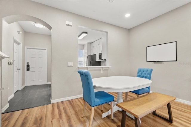 dining space featuring baseboards, arched walkways, and wood finished floors