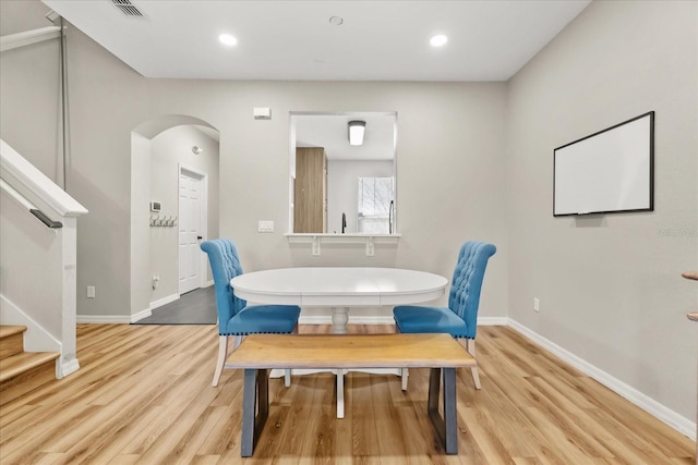 dining space with stairway, baseboards, light wood finished floors, recessed lighting, and arched walkways