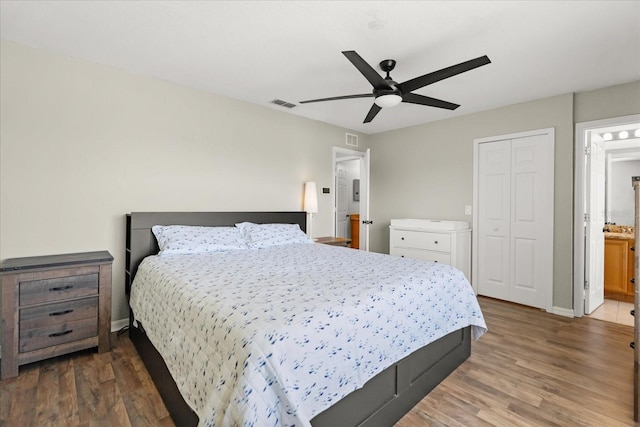 bedroom with a ceiling fan, wood finished floors, visible vents, baseboards, and a closet