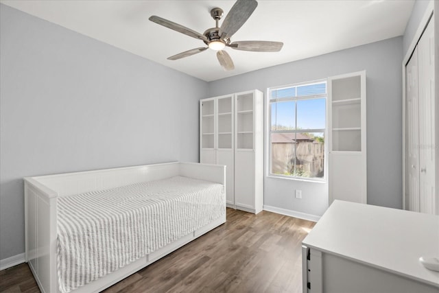 bedroom featuring ceiling fan, a closet, baseboards, and wood finished floors