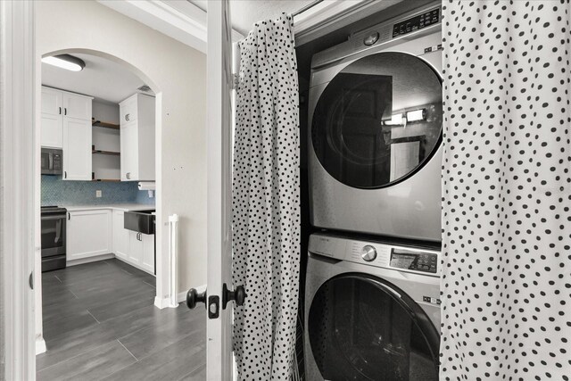 122 Capri Dr, Davenport, FL 33897 - washroom with stacked washer and clothes dryer, arched walkways, and dark wood-style floors